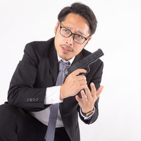 周囲を警戒しながら拳銃に弾倉を装填する会社員の写真