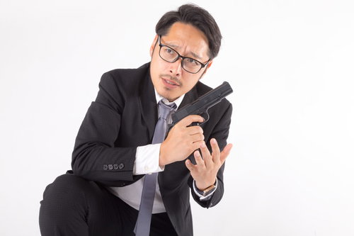 周囲を警戒しながら拳銃に弾倉を装填する会社員