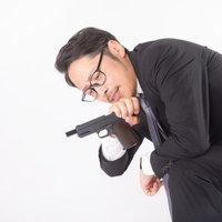 弾詰まりと時間を同時にチェックする殺し屋の男性の写真