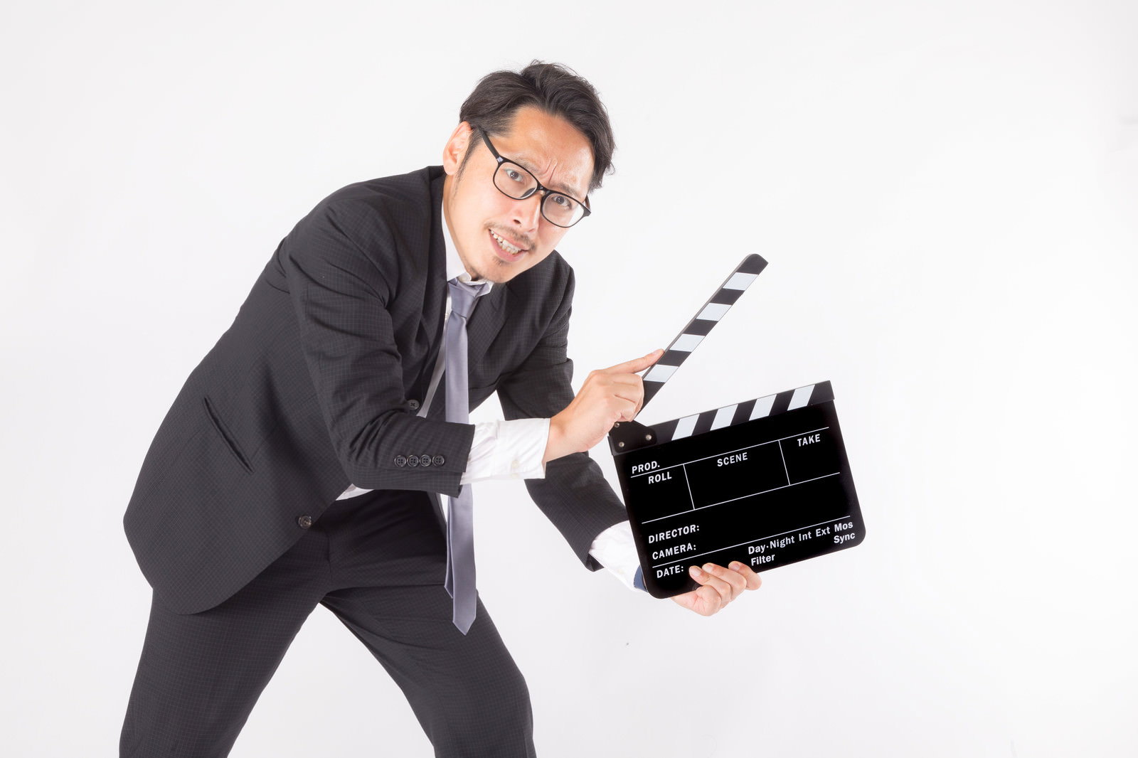 黒いスーツを着た会社員がカチンコを持って立っている［モデル：ゆうせい］