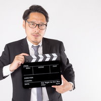 緊張感ある現場のカチンコ役を務めるスーツの男性（本番）の写真