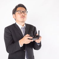 ドローンを飛ばす部長職の男性がプロポを操縦の写真