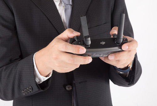 黒いスーツを着たビジネスマンがドローンのプロポを両手で操作