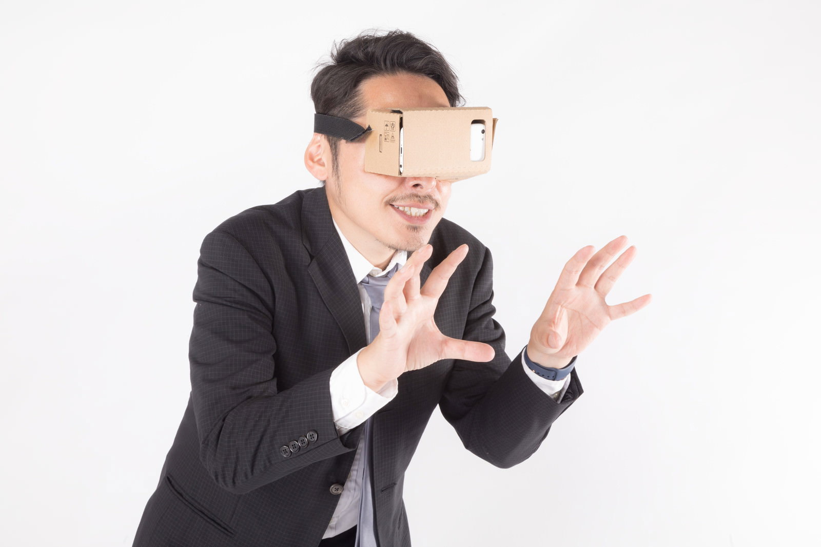 VRゴーグルをつけて両手で何かを揉む動作をする黒いスーツの男性［モデル：ゆうせい］