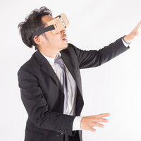 VRヘッドセットを装着して仮想現実の中を彷徨う会社員の写真