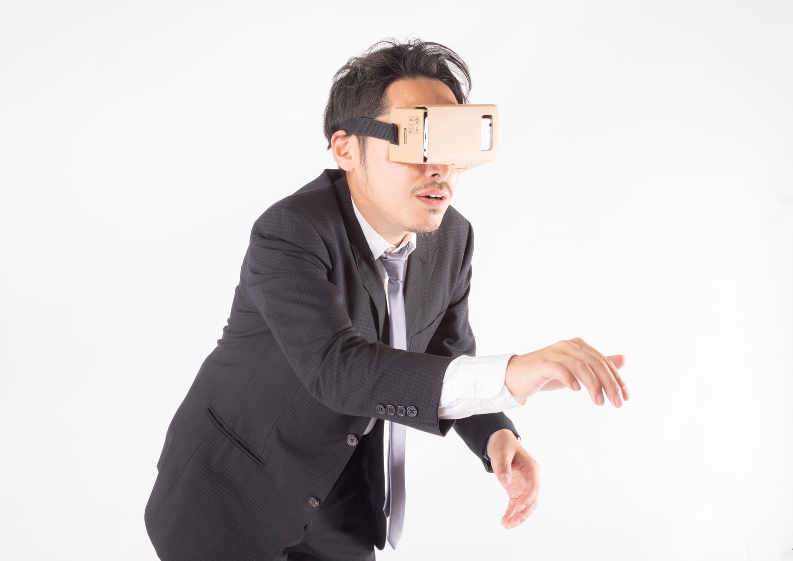 VRゴーグルを装着してスーツを着た男性がスイッチを押している［モデル：ゆうせい］