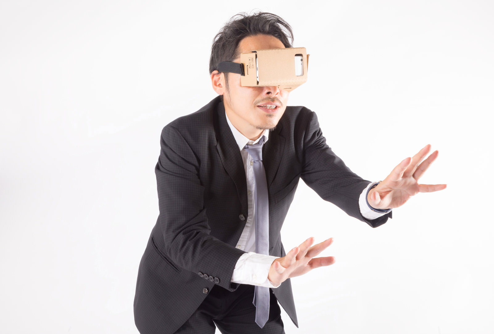 VRゴーグルをつけて両手を広げ困惑する黒いスーツの男性［モデル：ゆうせい］