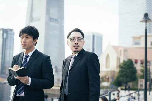 観光地で聞き込み捜査をする刑事と記者の取材風景