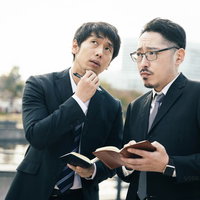 取材中に手帳を見ながら困難な案件について相談する刑事の写真
