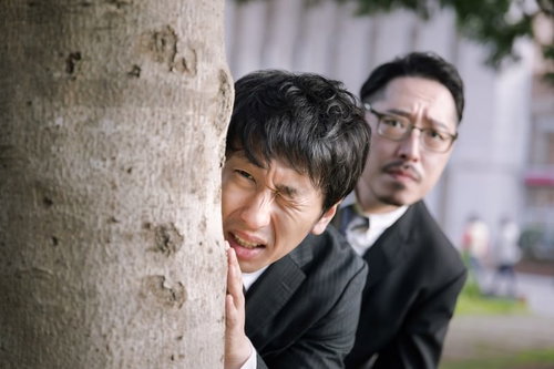見てはいけないものを見てしまった刑事・木陰で身を隠すスーツ姿の男性