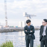 捜査中に談笑する刑事と記者の港での会話風景の写真