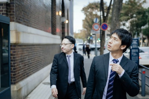 先輩、ここを右です おう スーツ姿の記者が聞き込み調査