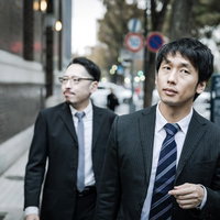 街中で聞き込み調査する刑事と記者のスーツ姿の男性の写真