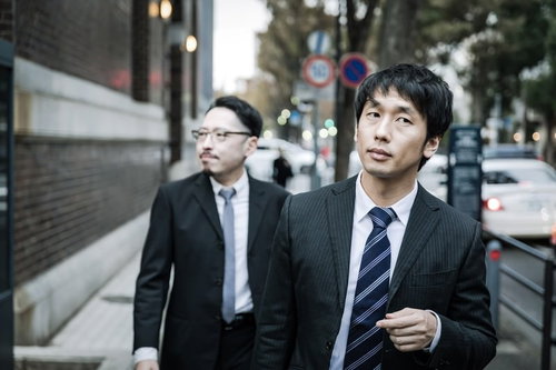 街中で聞き込み調査する刑事と記者のスーツ姿の男性