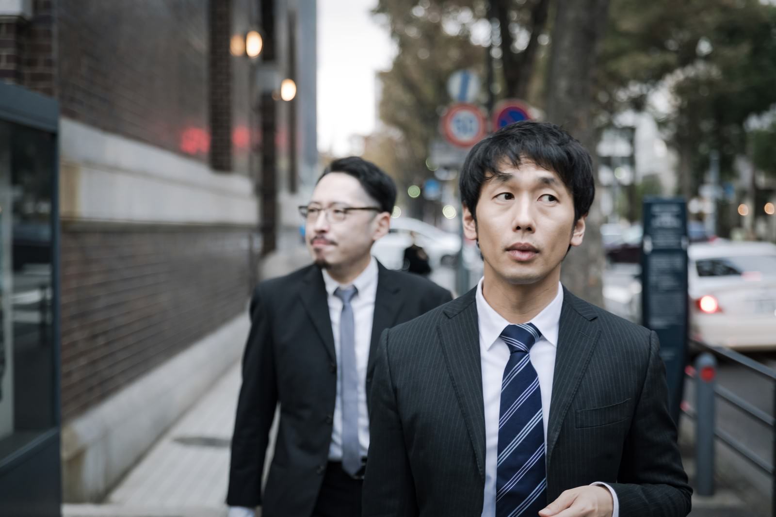街中でターゲットを探すスーツ姿の男性記者［モデル：大川竜弥 ゆうせい］