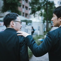 年上の部下を励ます会社員の応援シーン、肩に手を置き支援する職場のビジネス場面の写真