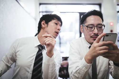 スマートフォンの画面を覗き見するスーツ姿の男性