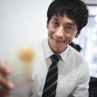 スーツ姿でレモンサワーを持ち乾杯する男性の写真