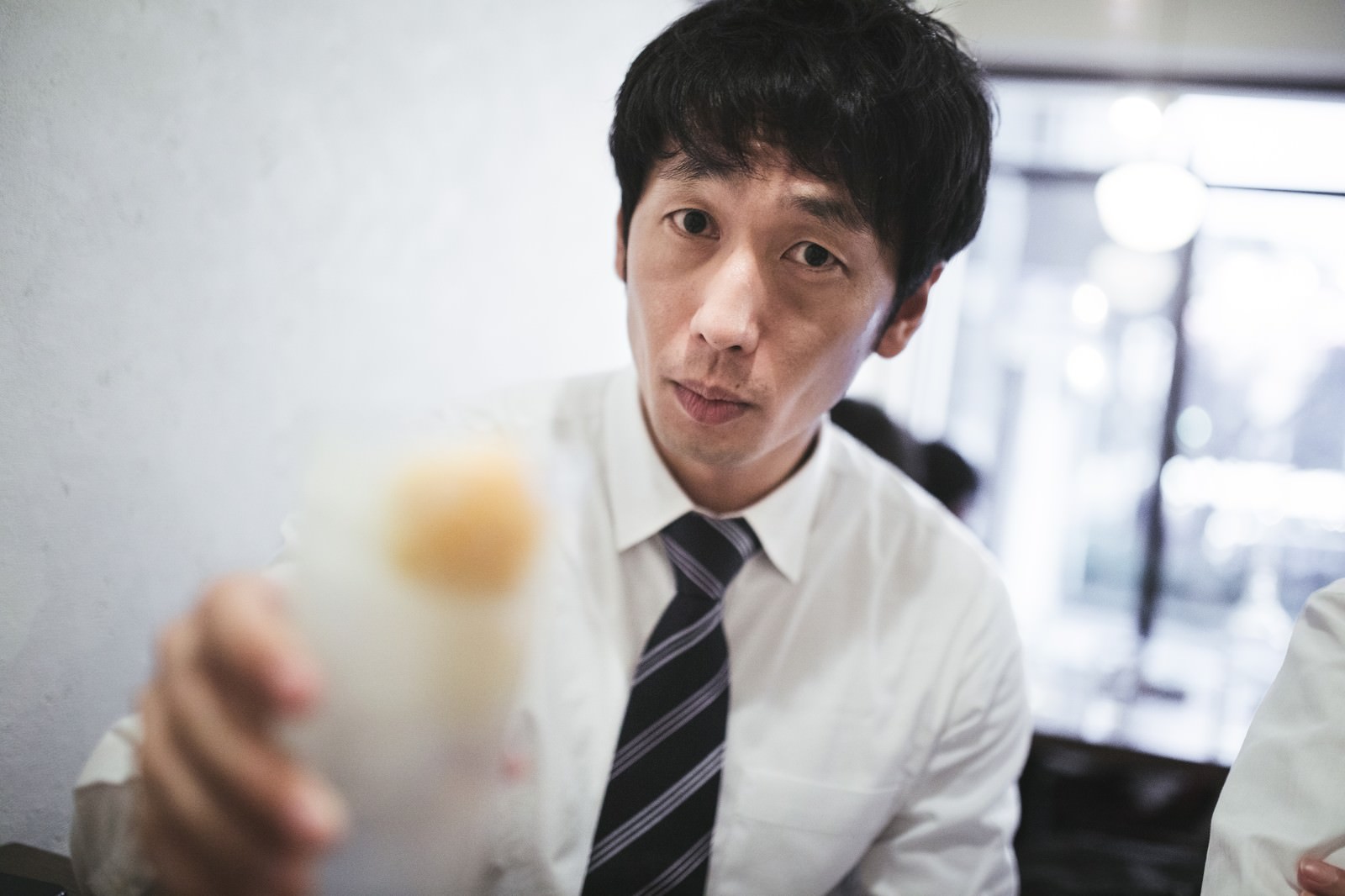 レモンサワーのグラスを持って乾杯するスーツ姿の男性［モデル：大川竜弥］