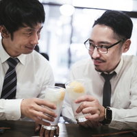 「今日もお疲れ」と乾杯する上司と部下の写真