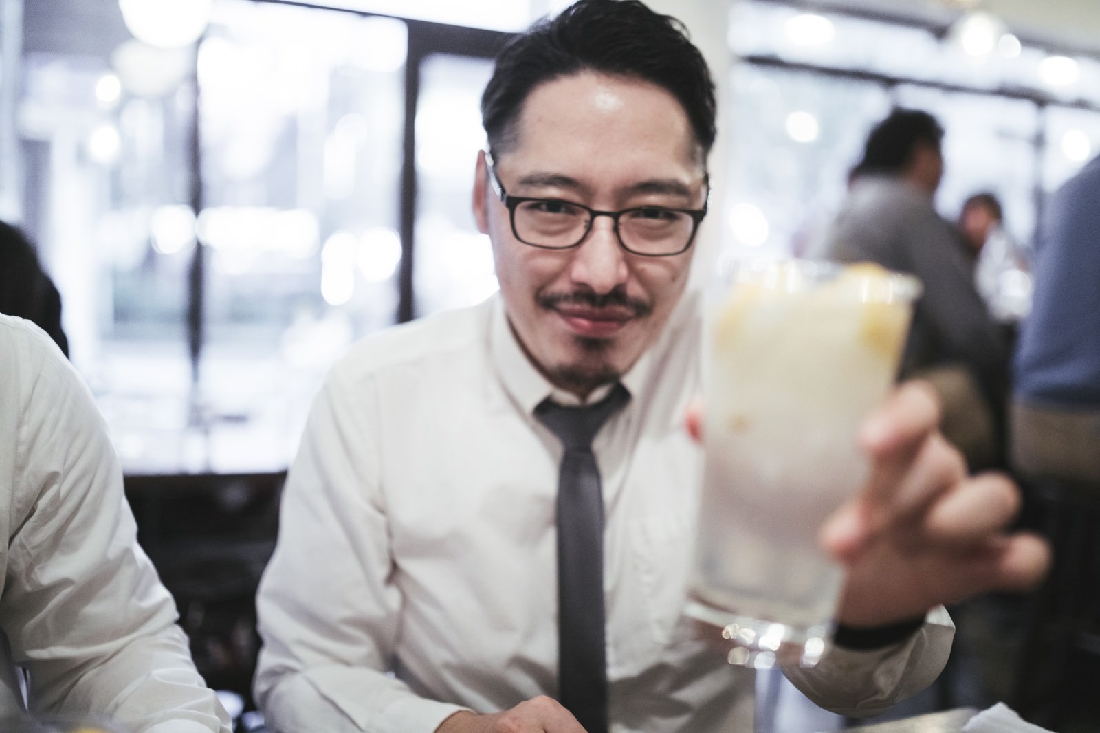 接待の宴会で浮かない顔をしているスーツ姿の男性会社員［モデル：ゆうせい］