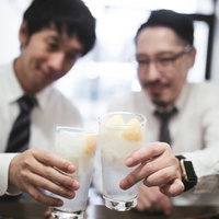 レモンサワーで乾杯するスーツ姿の男性の写真