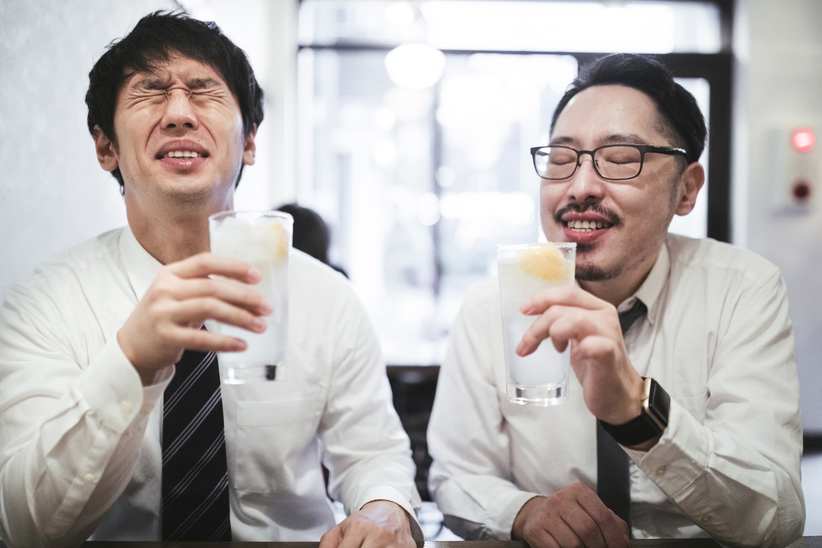 グラスを持って乾杯するスーツ姿の男性二人［モデル：大川竜弥 ゆうせい］