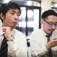 同僚のスマホを横から覗き見するサラリーマンの写真