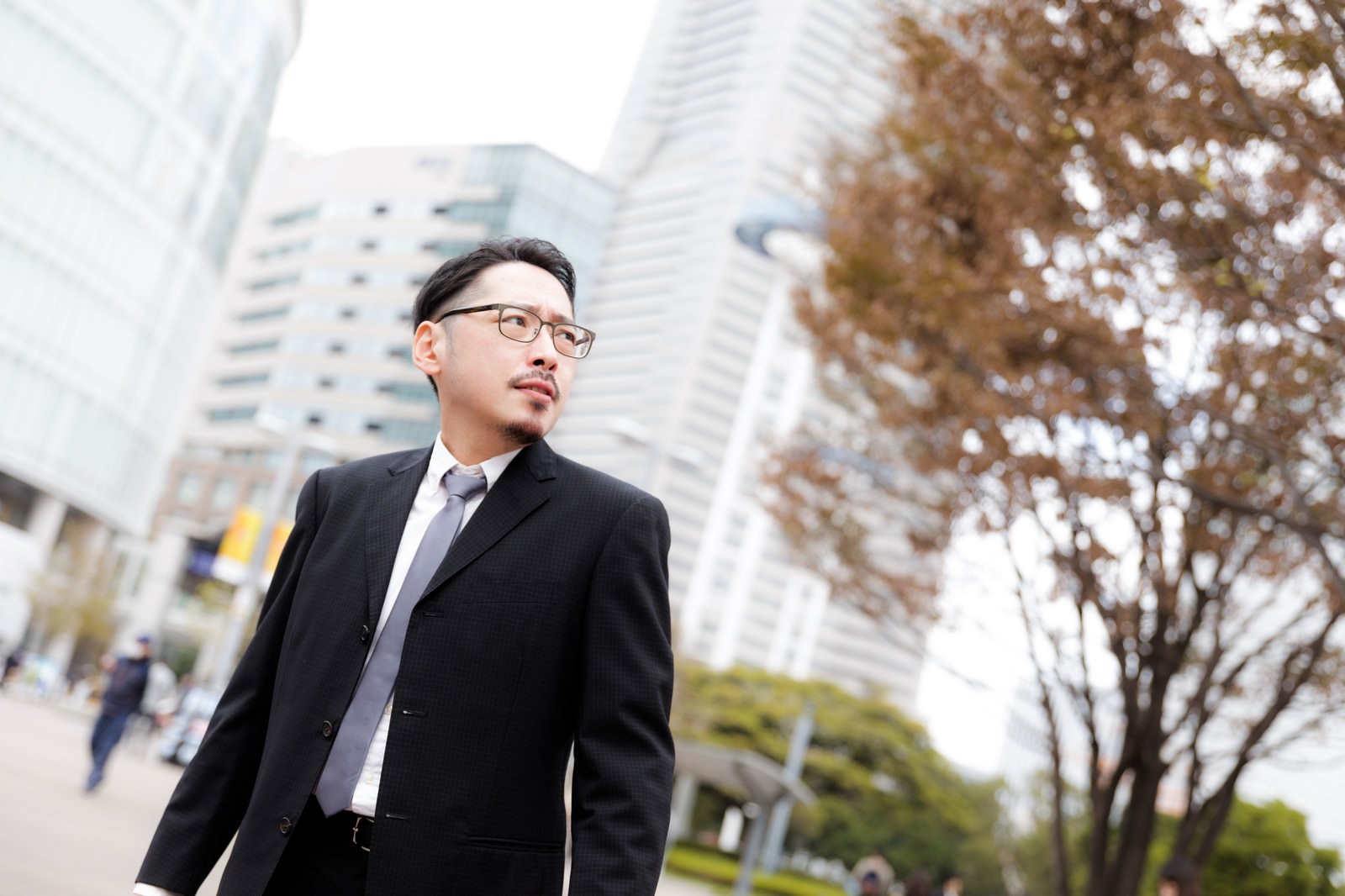 黒いスーツを着た男性が街中で周囲を警戒している刑事［モデル：ゆうせい］