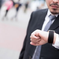 腕時計を見て時間を確認するスーツ姿の男性の写真