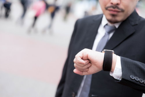 腕時計を見て時間を確認するスーツ姿の男性