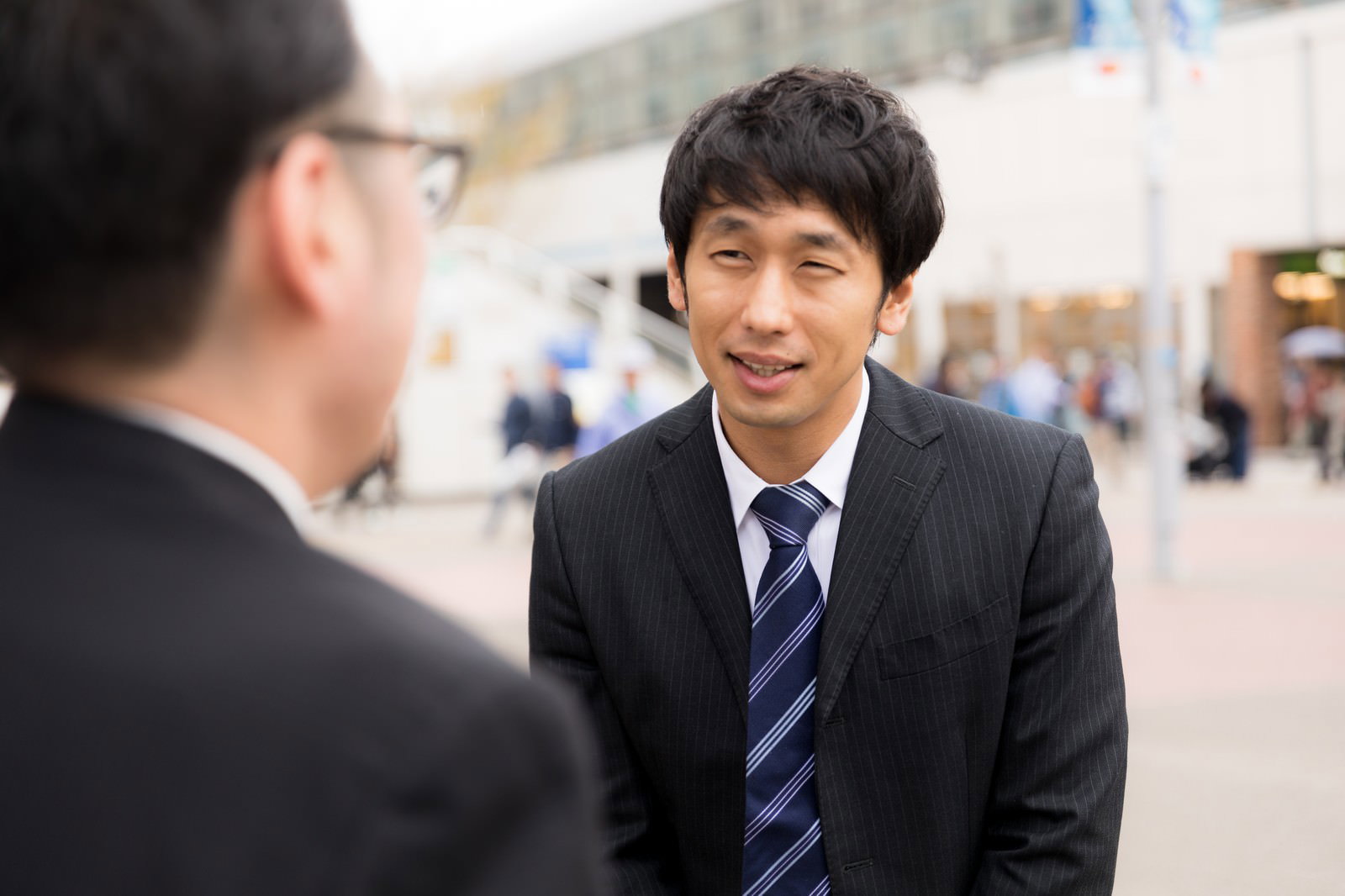 黒いスーツとストライプのネクタイを着た男性が謝罪している［モデル：ゆうせい 大川竜弥］