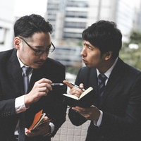 スーツ姿のジャーナリストと探偵が捜査情報を報告し合うの写真