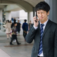 面接結果を聞いて落ち込むスーツ姿の男性の駅での失敗の写真