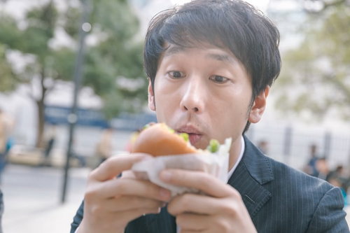 ピクルス抜いてって言ったのに、ハンバーガーをかぶりつく男性