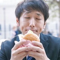 ジャンクフード大好きっ子、スーツ姿でハンバーガーをもぐもぐの写真