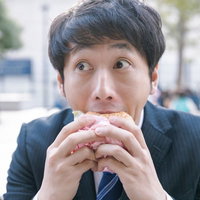 一心不乱にハンバーガーにかぶりつく会社員の写真