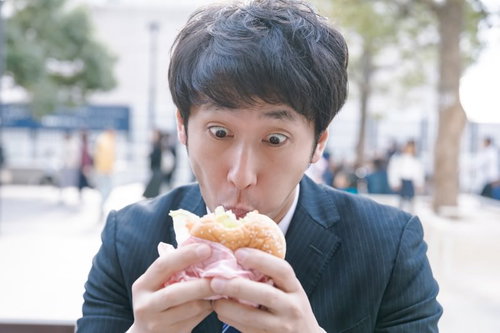 時間に追われて急いでハンバーガーを食べる社畜