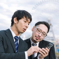 川沿いに立つスーツ姿の男性2人の写真