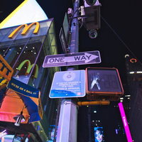 タイムズスクエアの夜間に立つワンウェイの標識と街灯のカメラの写真