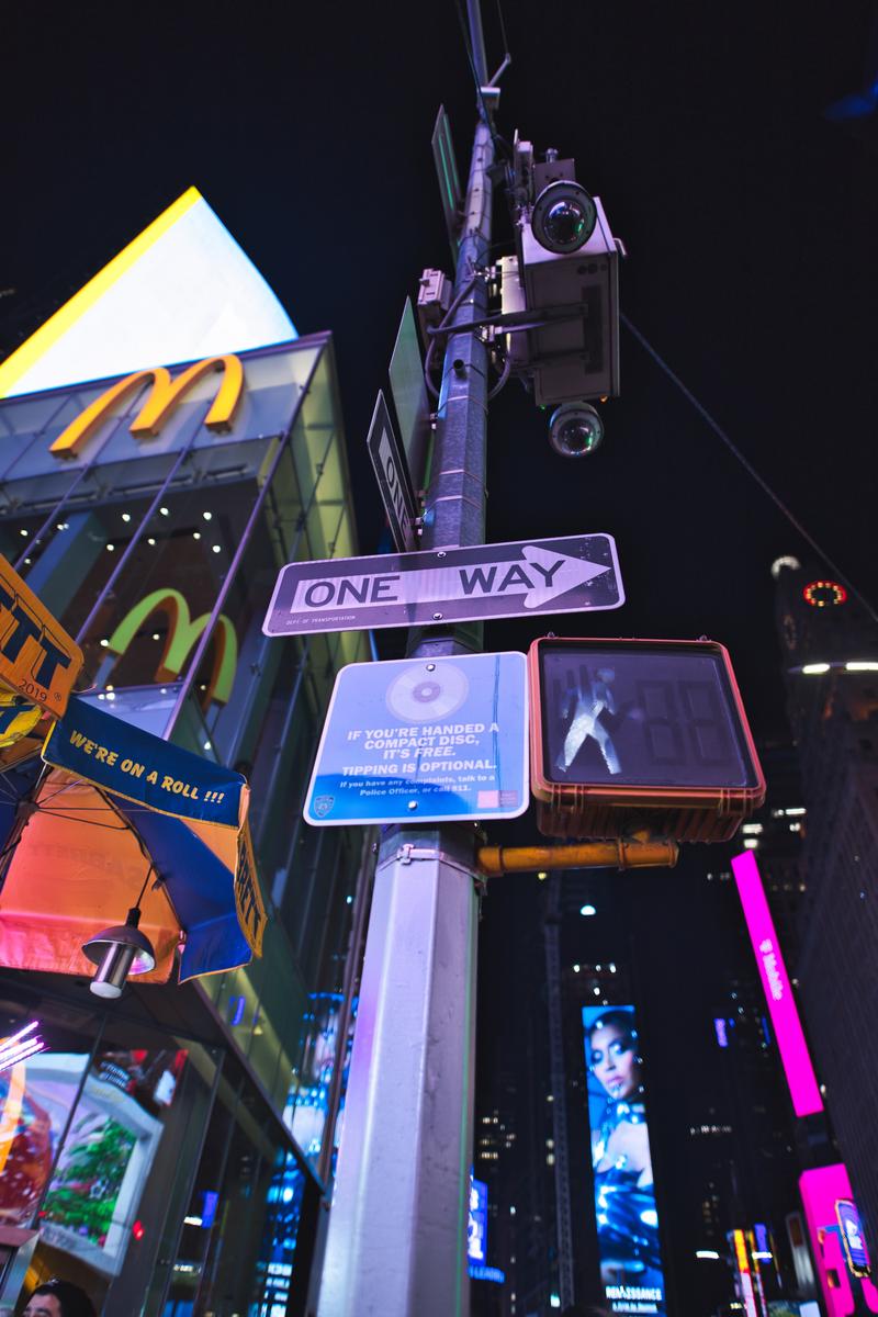 タイムズスクエアの夜景、ワンウェイ標識と街路灯、監視カメラが設置された都市風景
