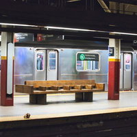 ニューヨークの地下鉄ホームに置かれた木製ベンチの写真