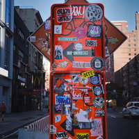 ニューヨークの街中に立つステッカーだらけの看板の写真