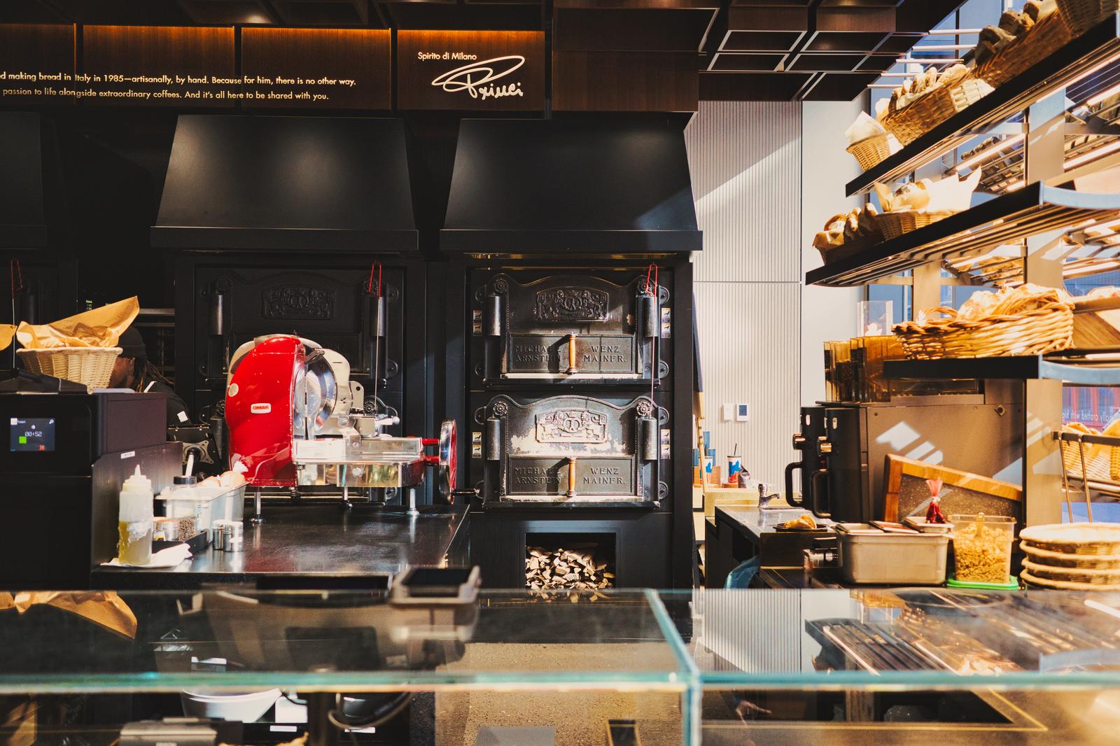 ニューヨークのパン屋の厨房で、赤いオーブンと石窯の前にバゲットが並ぶ