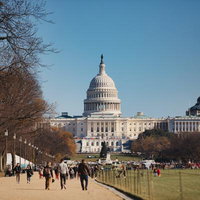 ワシントンD.C.の歩道から見るアメリカ国会議事堂と行き交う人々の写真
