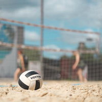 砂浜に置かれたビーチバレーボールと青空のビーチスポーツシーンの写真