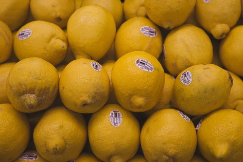 バーコード付きで並べたレモン、スーパーの青果売り場に積み重ねられた新鮮な柑橘類