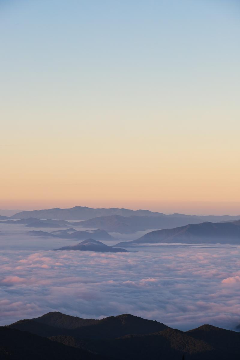 雲海に浮かぶ山々を朝焼けが照らす風景