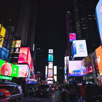タイムズスクエアの夜景、カラフルなビルボードと人混みの写真
