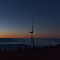山並みを望む鉄塔と雲海に映える朝焼けの日の出風景の写真